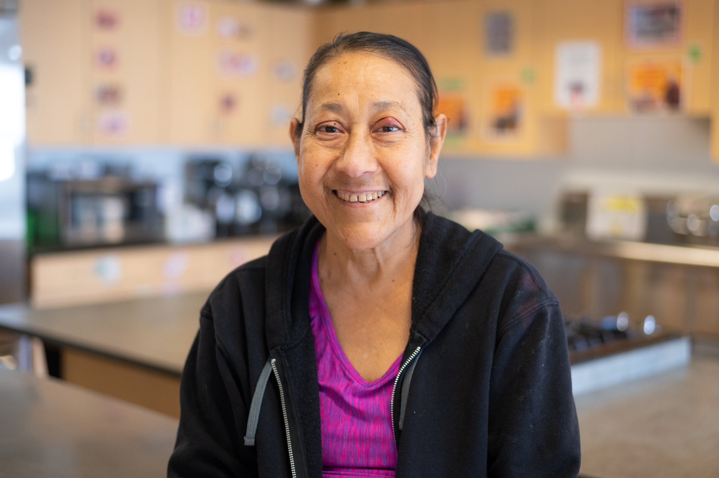 Gloria Padilla Sanchez sits in the Metro Caring kitchen smiling at the camera