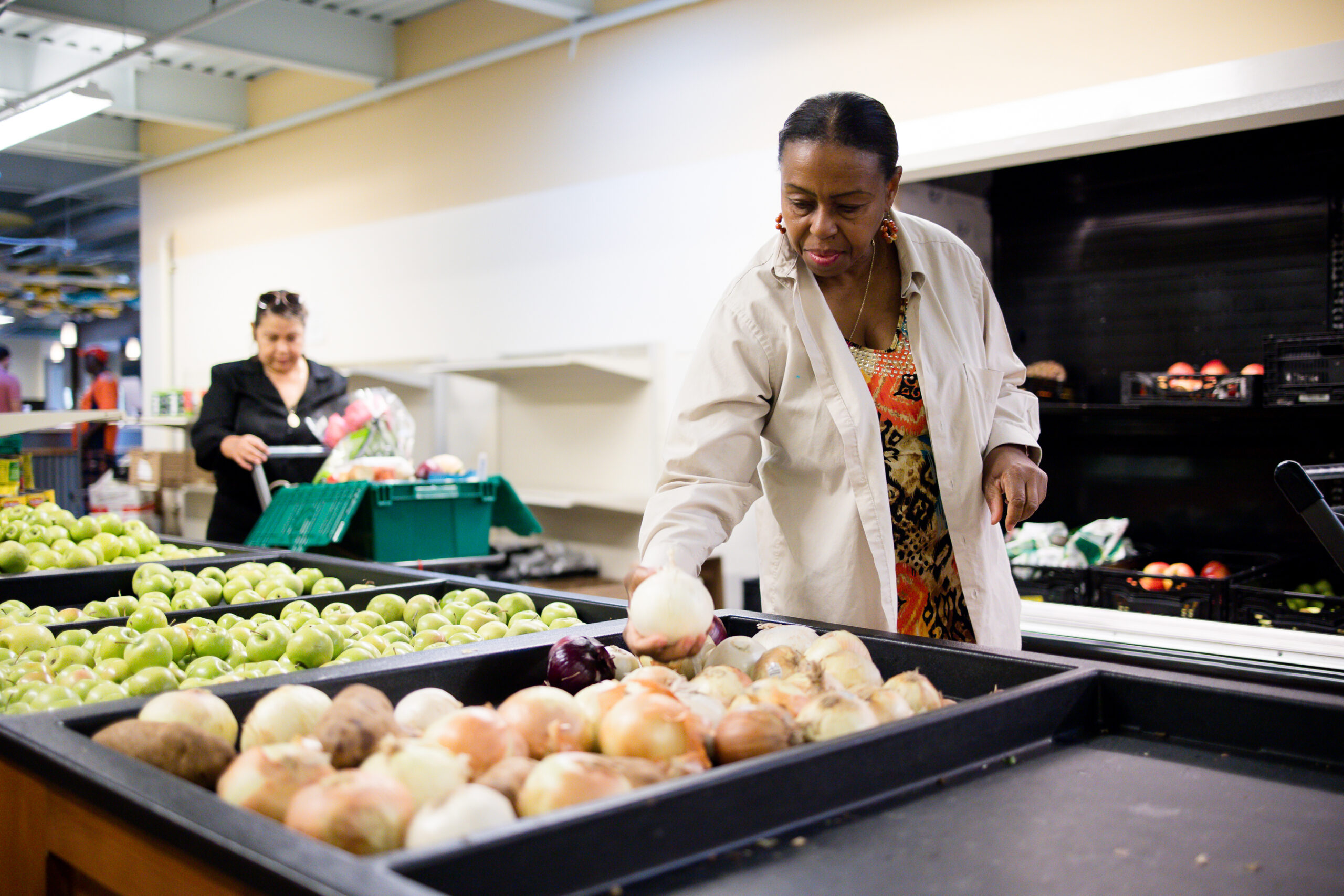 Fresh Foods Market shopper picks up onions from the produce bins in the Fresh Foods Market. 