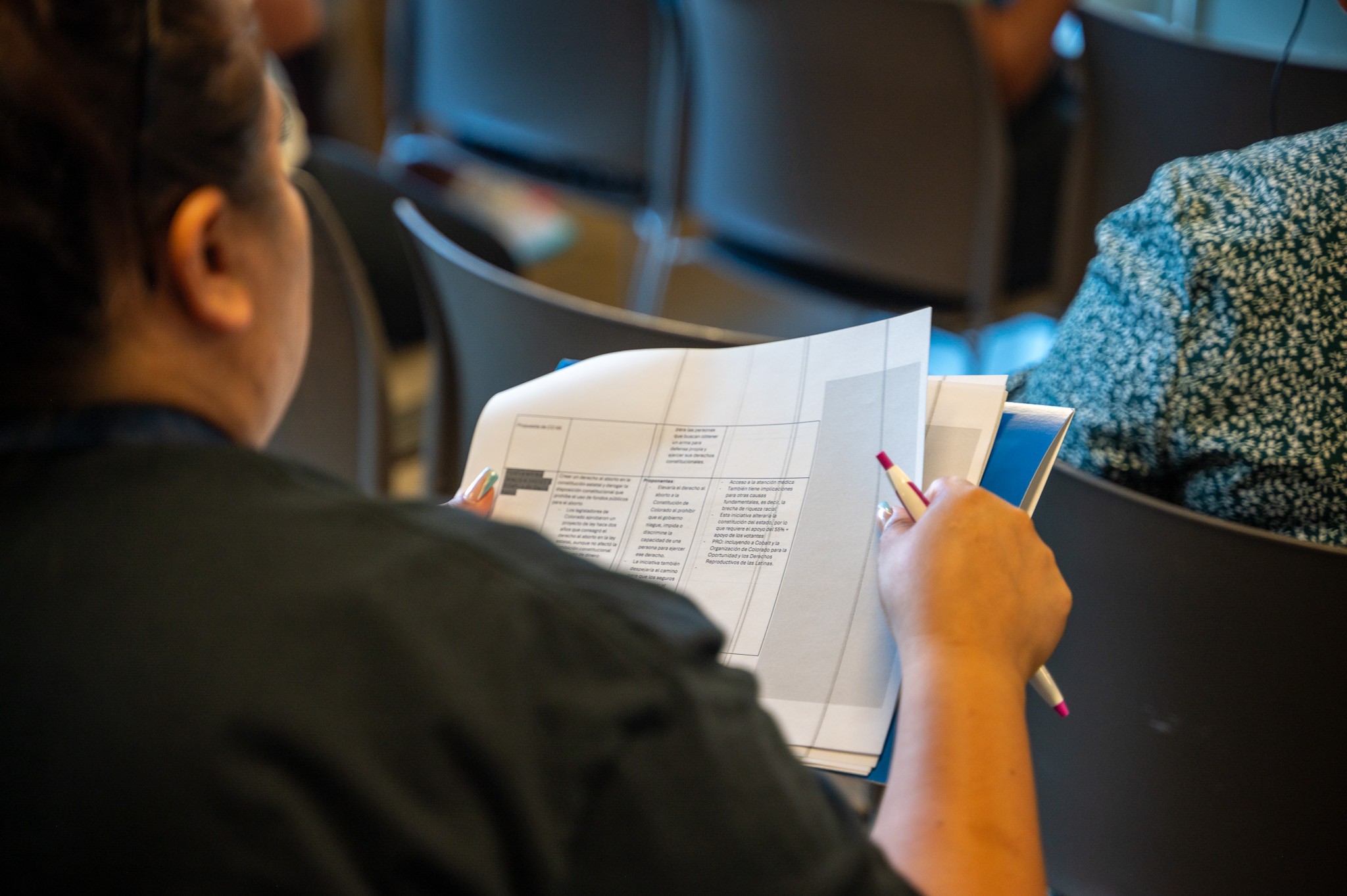 Photo over the shoulder of a community member looking at a packet of information about the ballot.