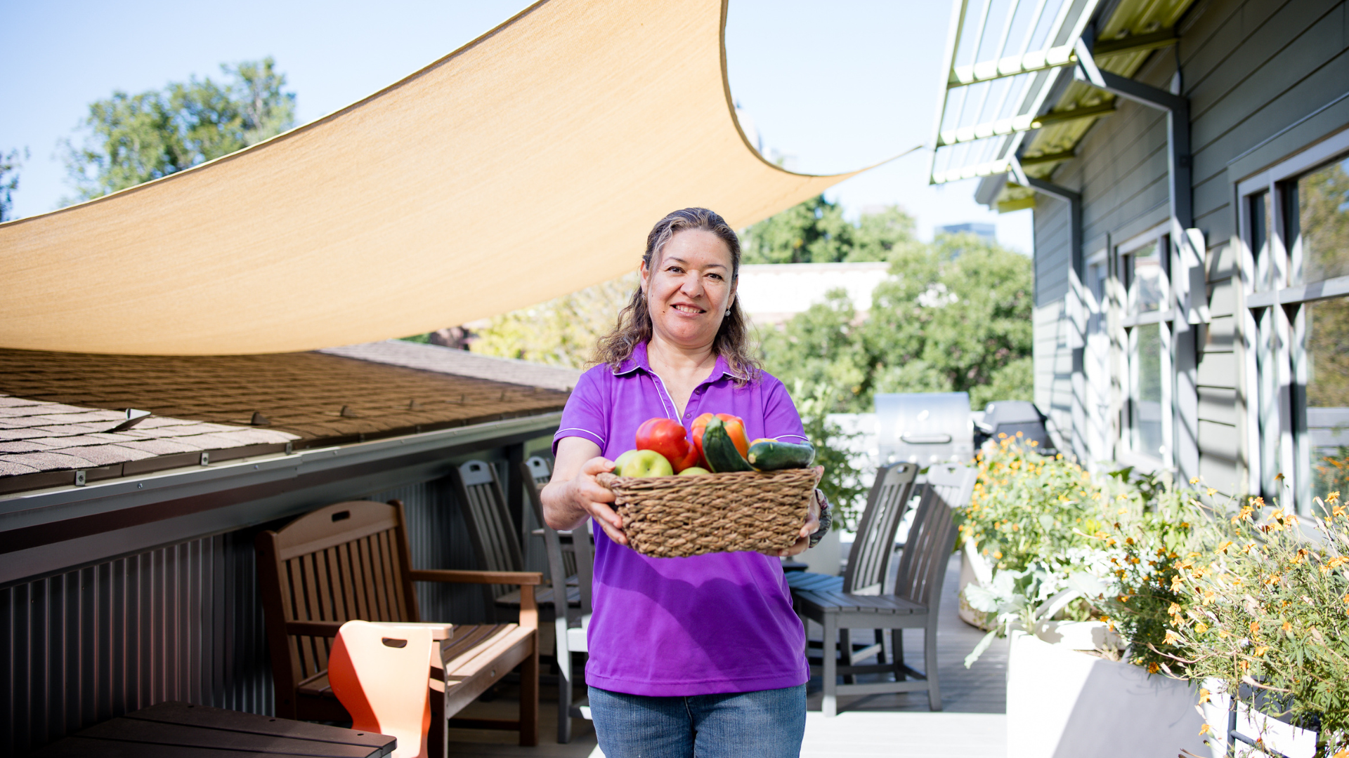 Woman holds out a basket of fruit while smiling.