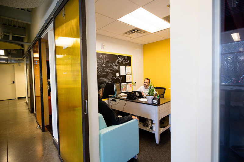 A community member sits in a meeting room with an Connector (not pictured) reading a paper with a calm smile. 