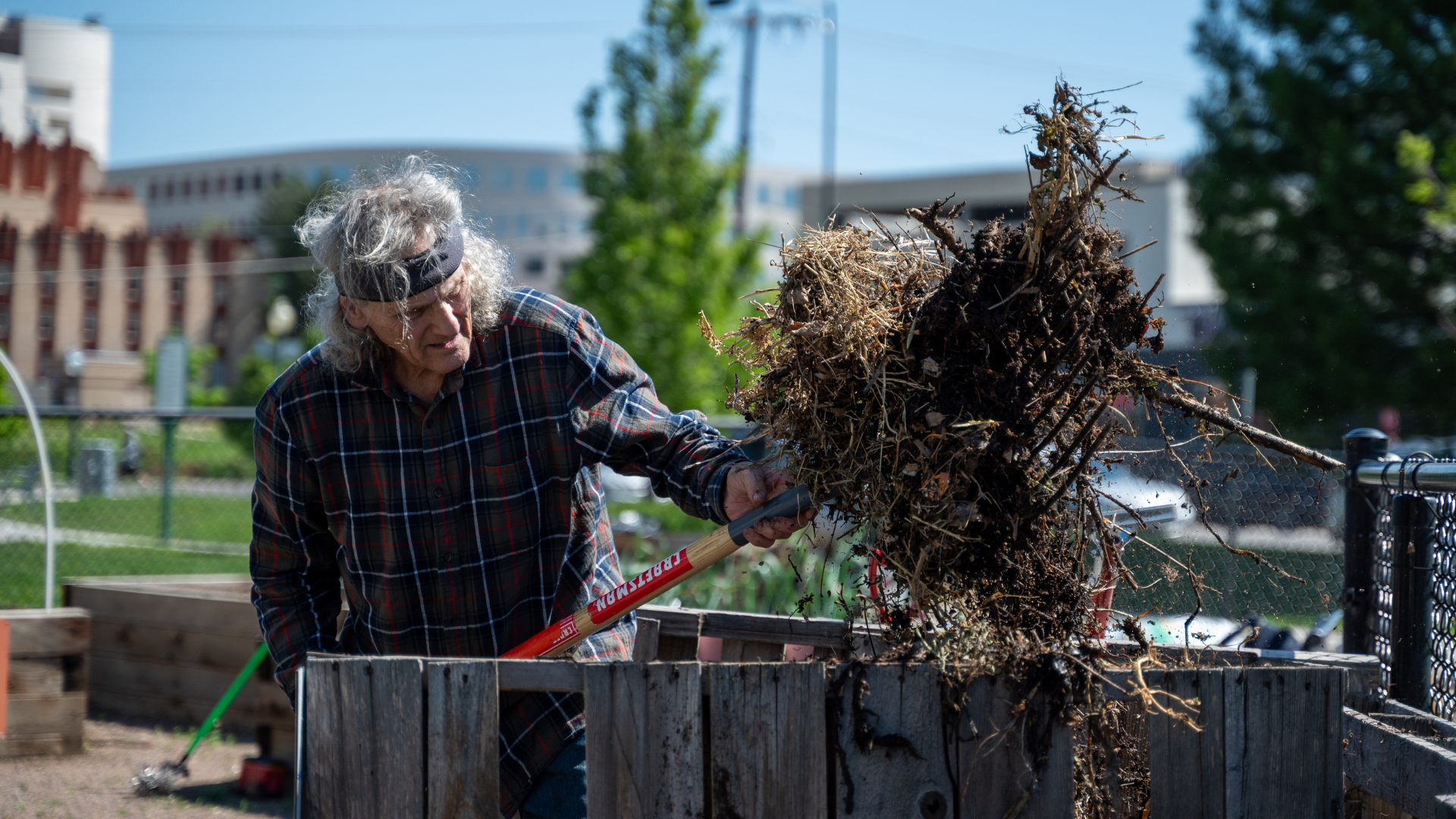 Randle heaves a large bundle of dried plants into the compost.