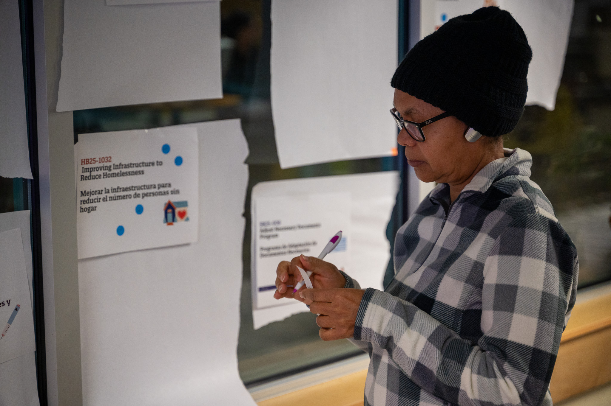 Eva peels off a sticky to place a vote on one of the 10 bills taped to the wall.