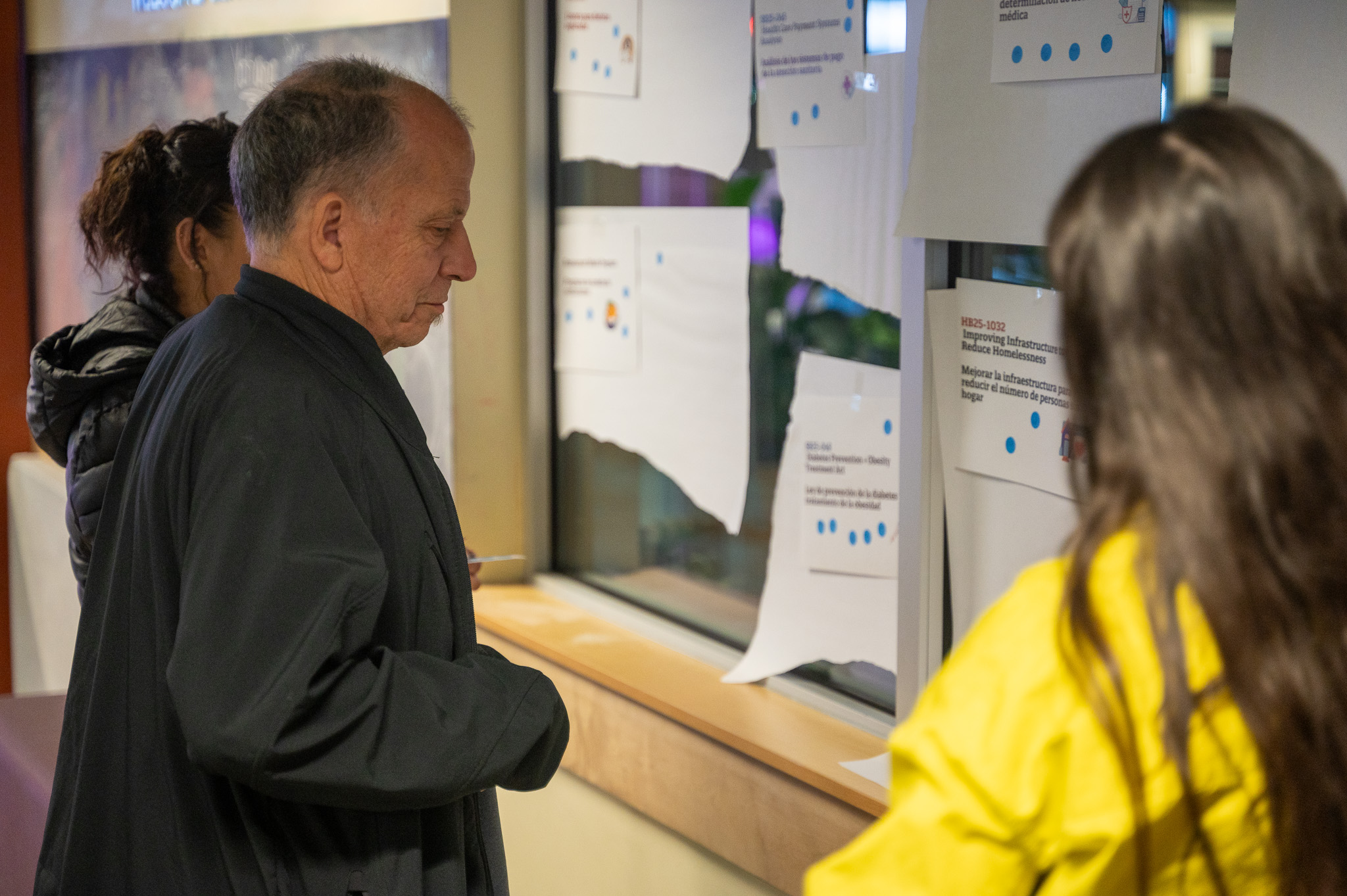 Jeff looks at several pieces of paper taped to the windows each listing different bills as he determines his vote.