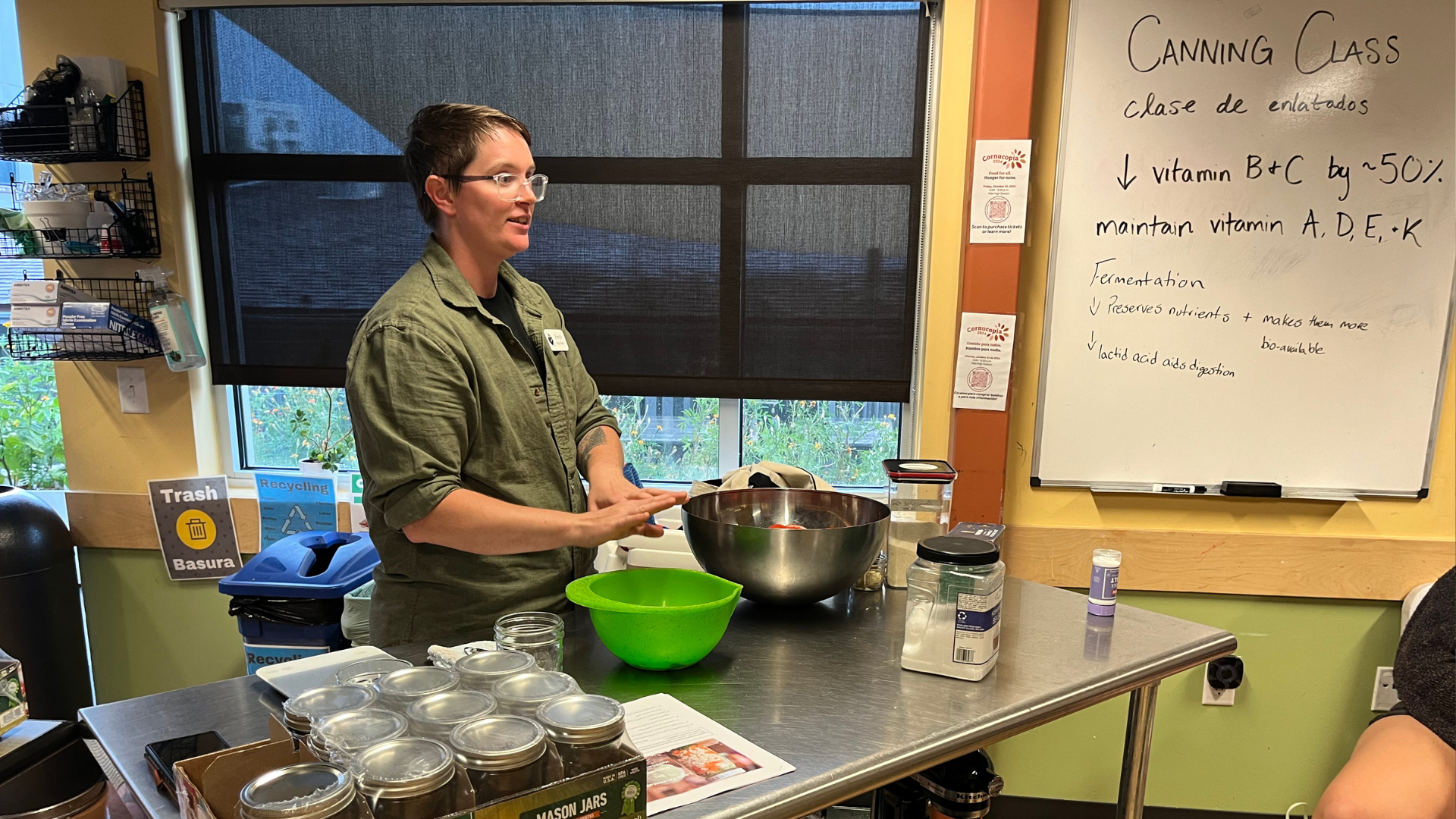 Ewan teaches a class about canning, standing behind a table with various mixing bowls and mason jars.