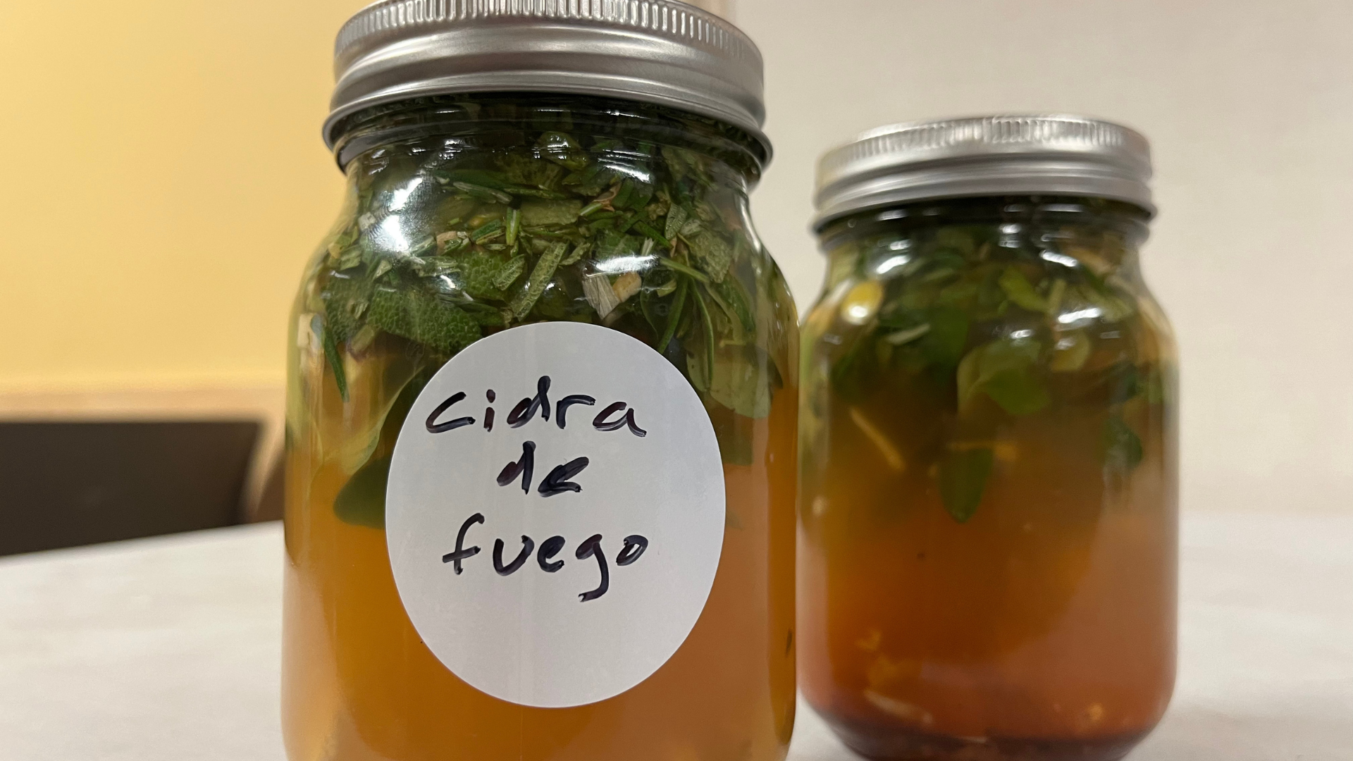 Mason jar full of fire cider. A handwritten label reads "cidra de fuego."