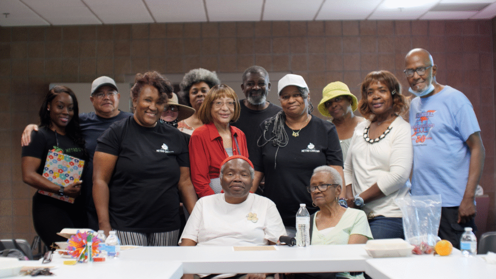 Black folks huddle around a table smiling at the camera at the Hiawatha Davis Recreation Center for Metro Caring's Diabetes Among Friends program.