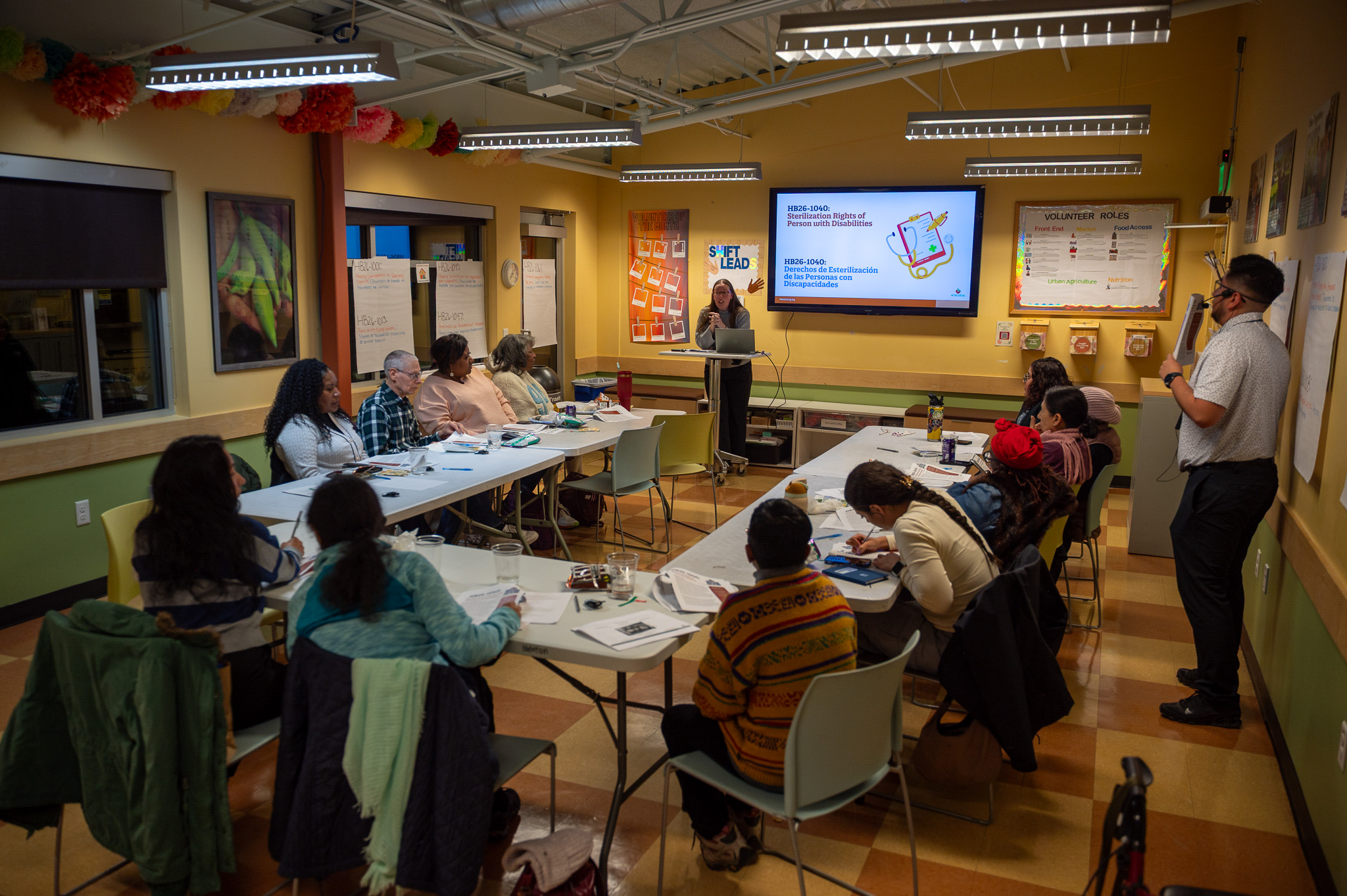 Community leaders sit around tables in Metro Caring's education center listening to Madison present on bills being introduced this legislative session.