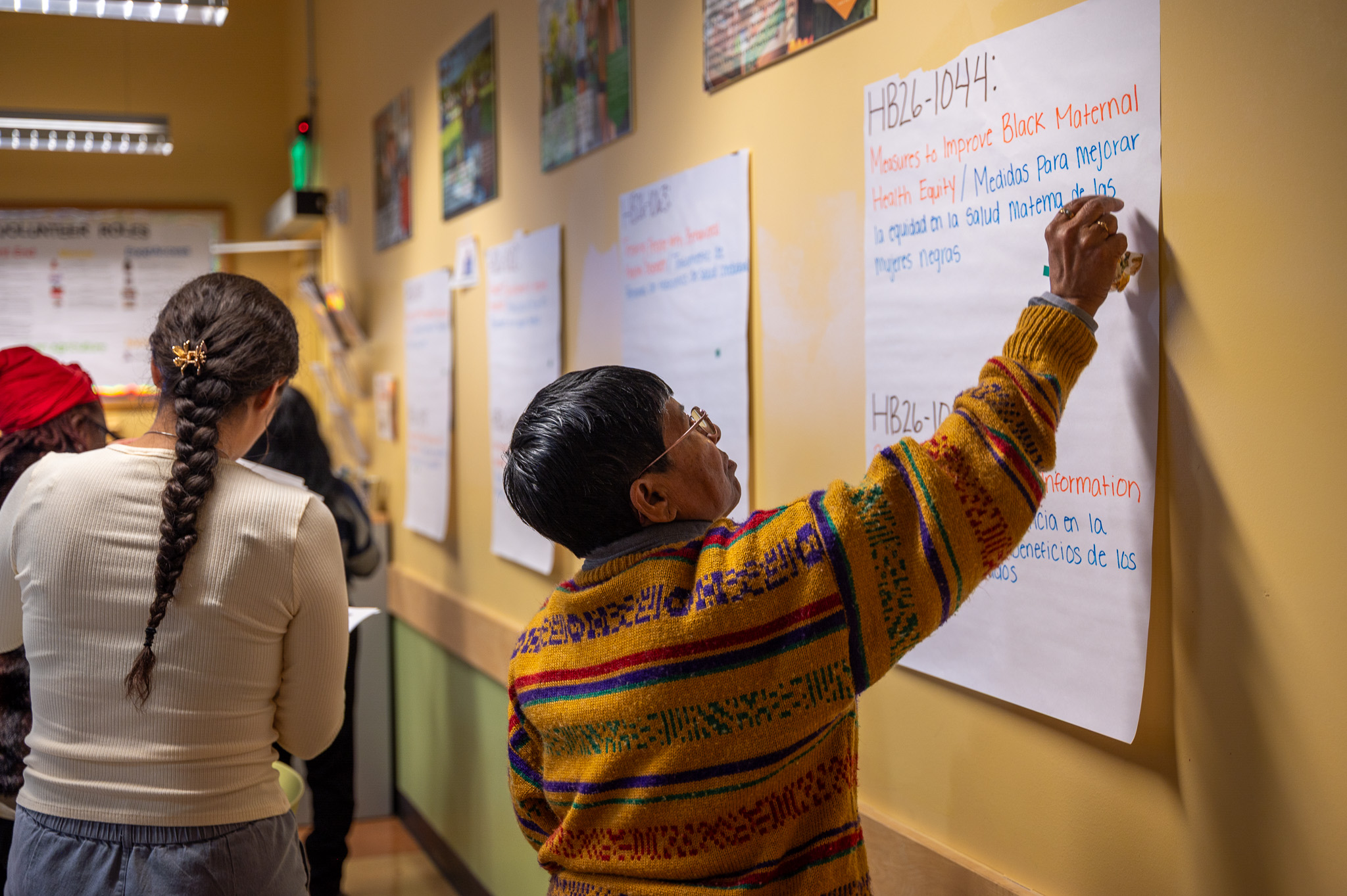 Pam places a sticker on a large white paper hanging on the wall to designate her vote to endorse Measures to Improve Black Maternal Health Equity.