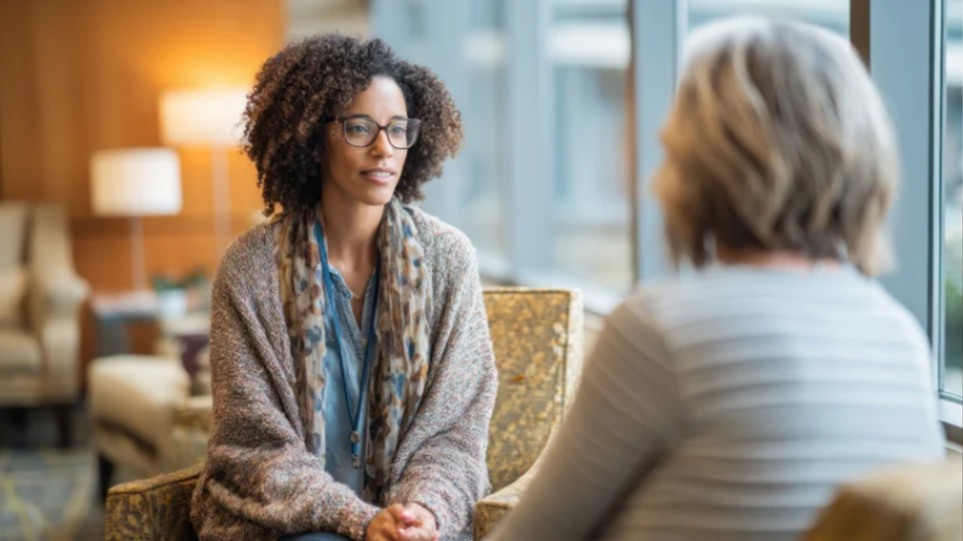 Woman speaks with another woman in a warm office environment.