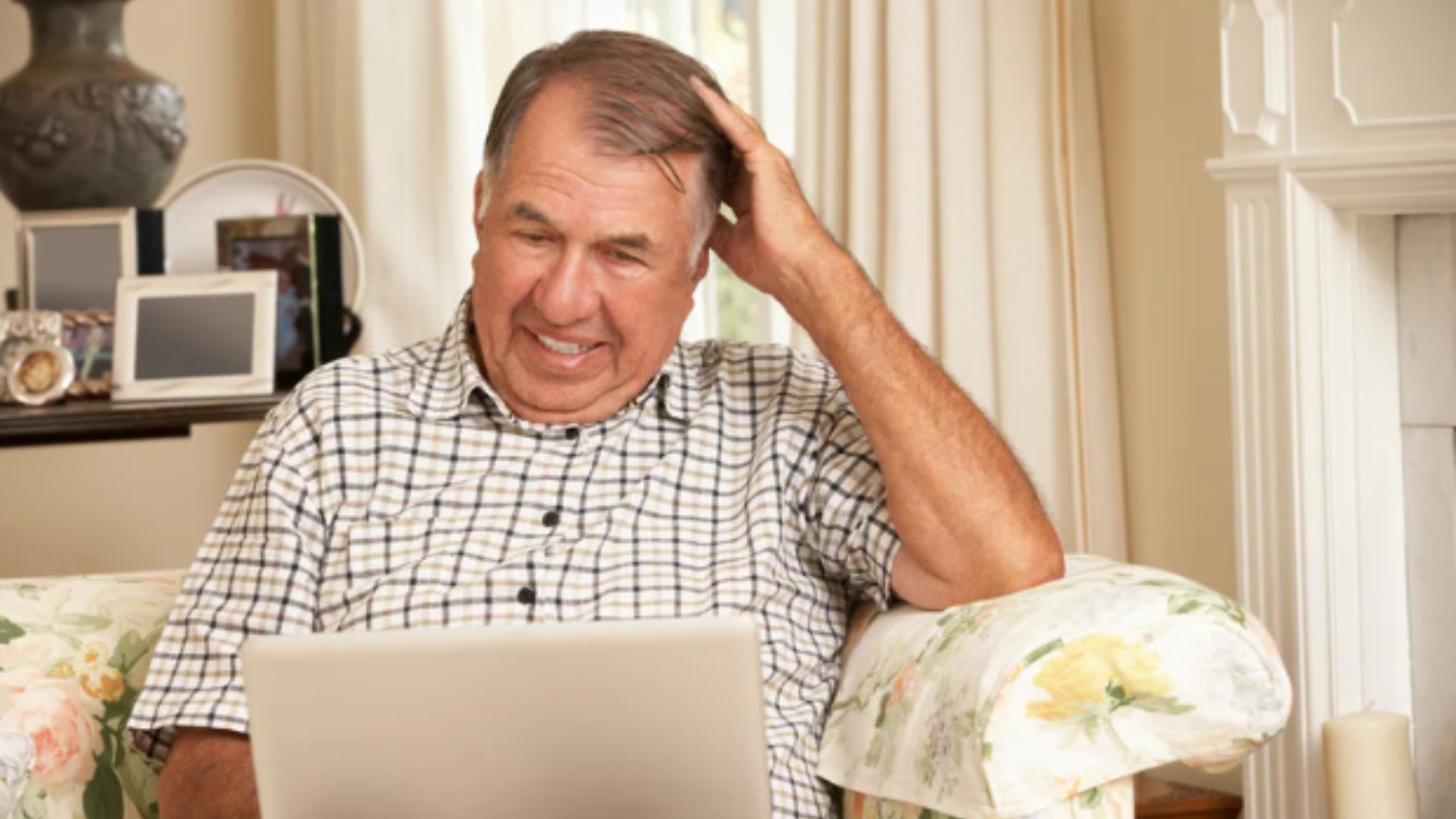 Man scratches his head while looking at a computer, mildly confused.