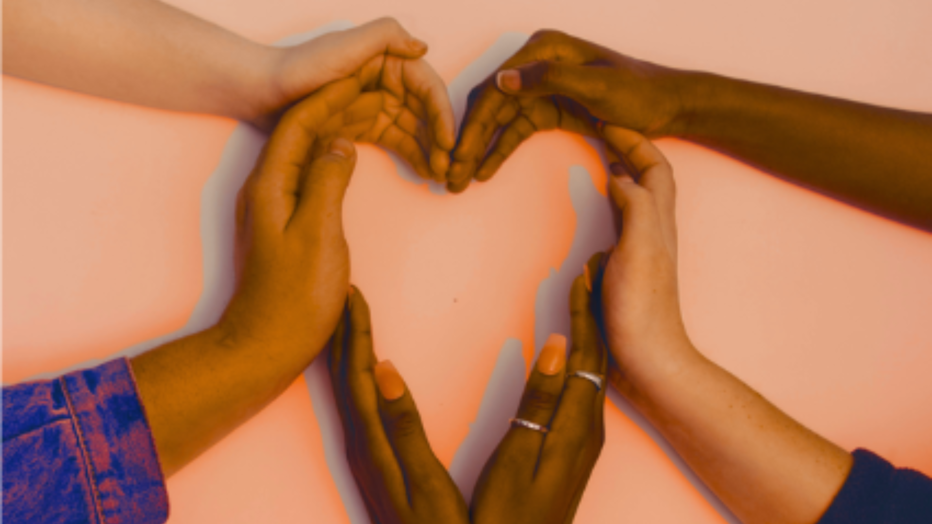 Hands of different skin tones come together to shape a heart.