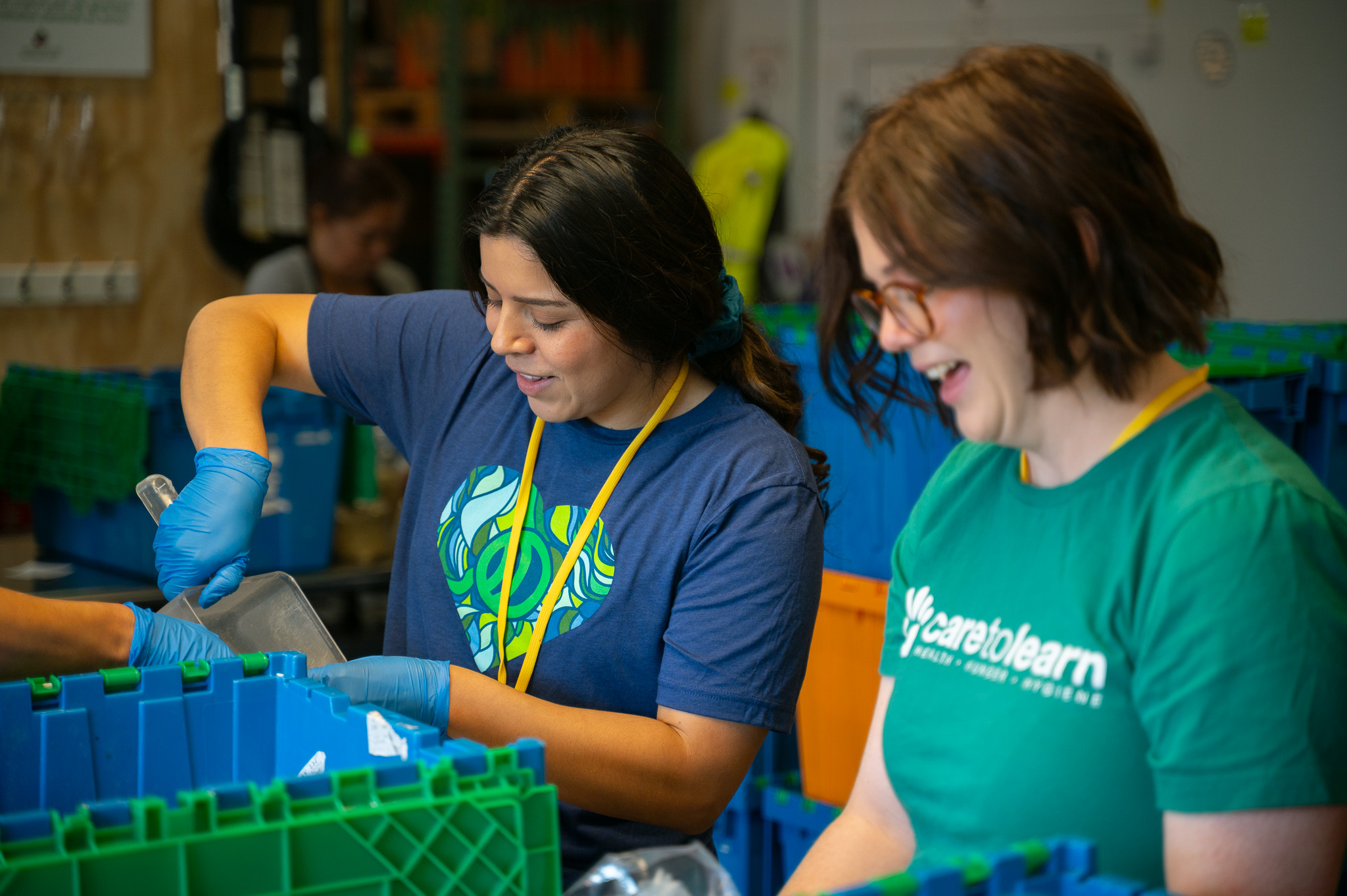 Volunteers spoon rice into bag wearing company shirts.