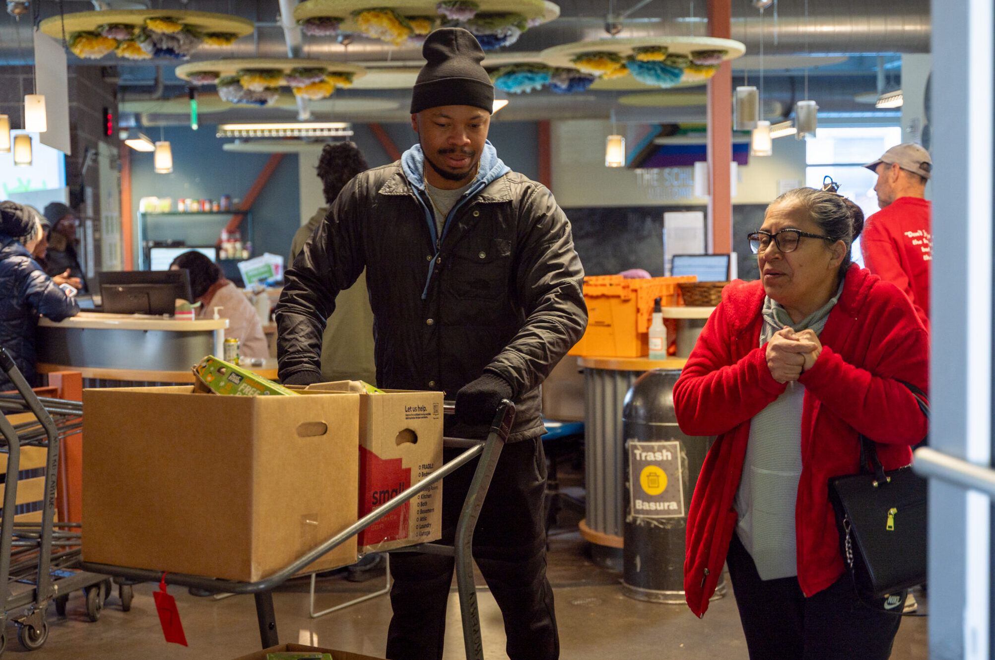 Volunteer helps a community member roll their cart out to their car.
